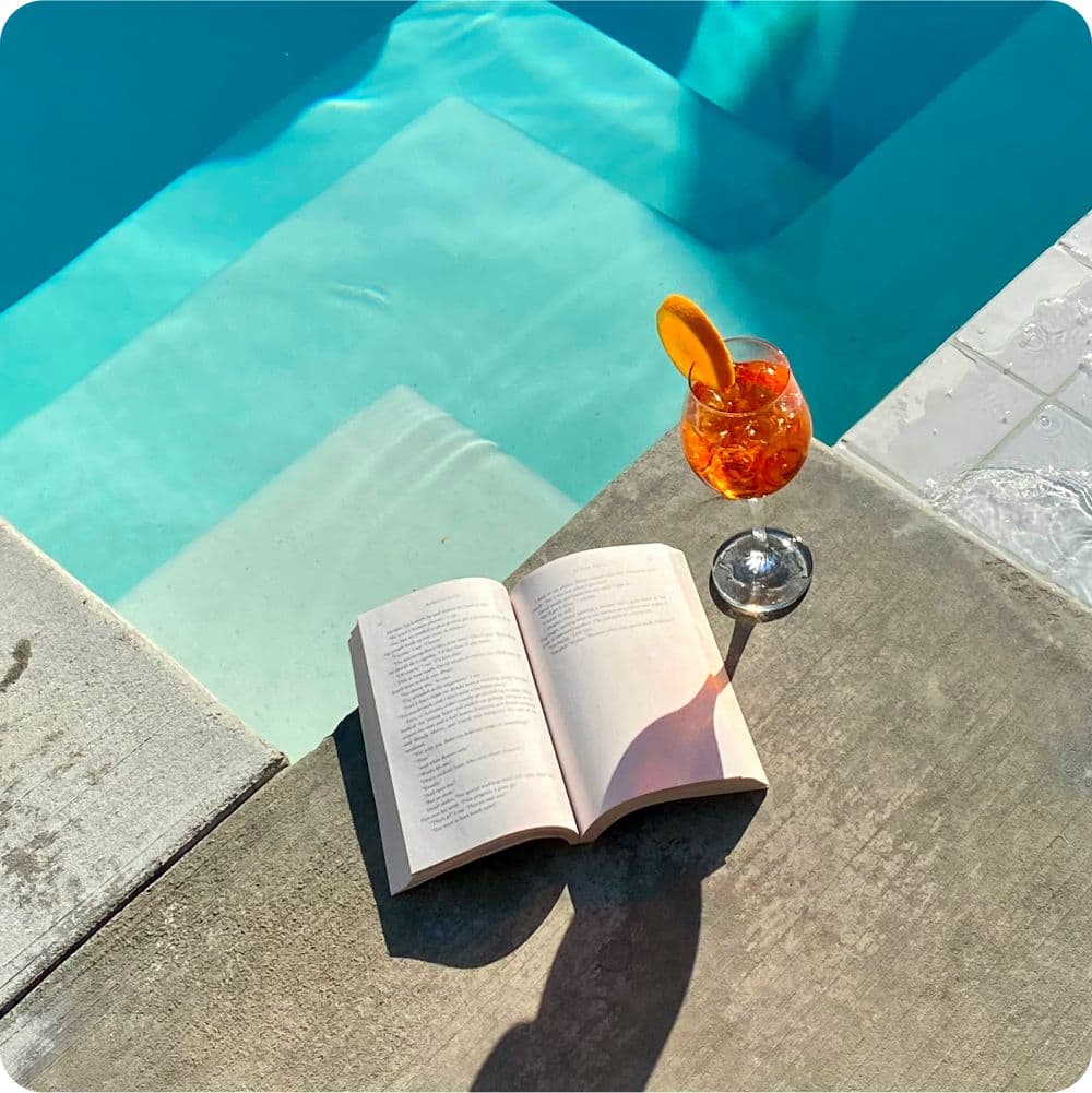 Pool side with book and cocktail